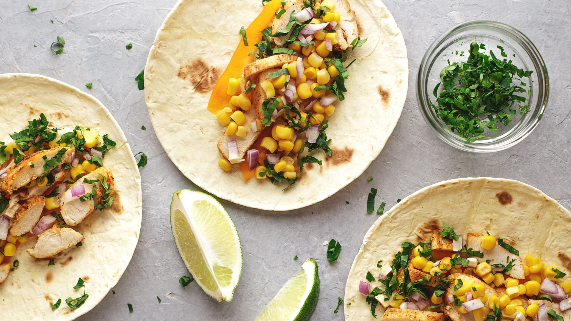 Latin American fast food tacos with chicken meat and vegetables on the gray stone background