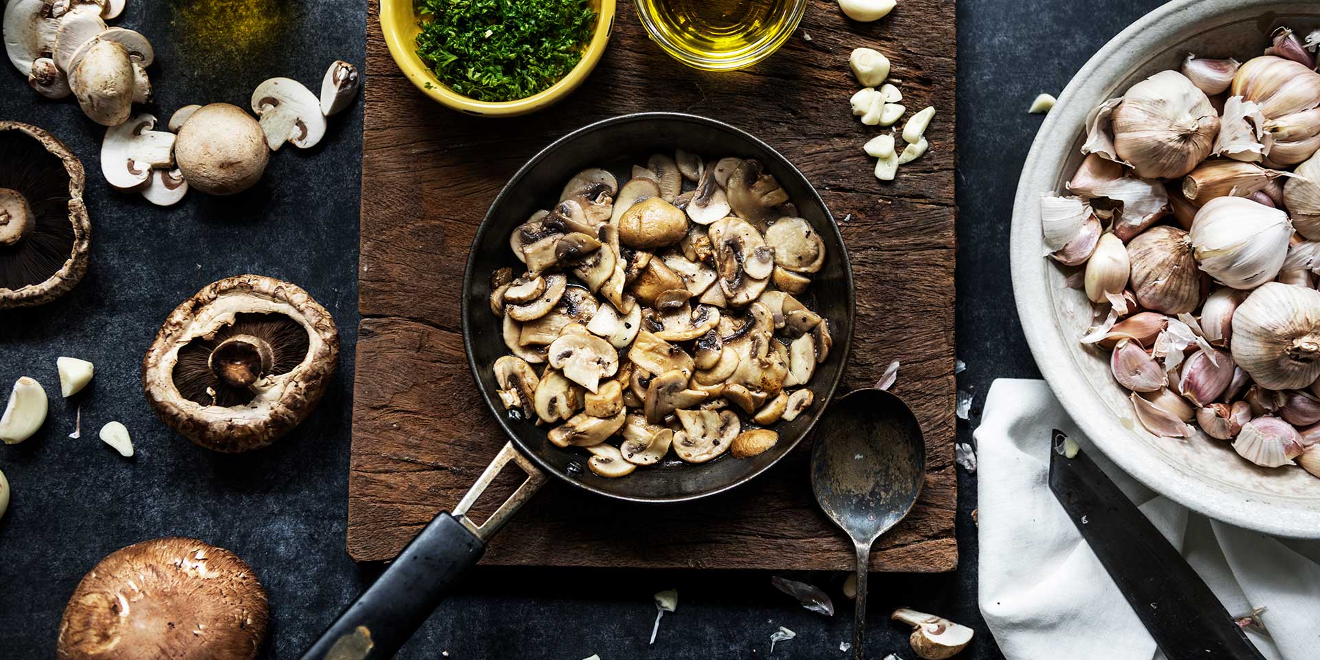 sliced mushroom pieces being cooked, garlic, herbs, portobello mushrooms