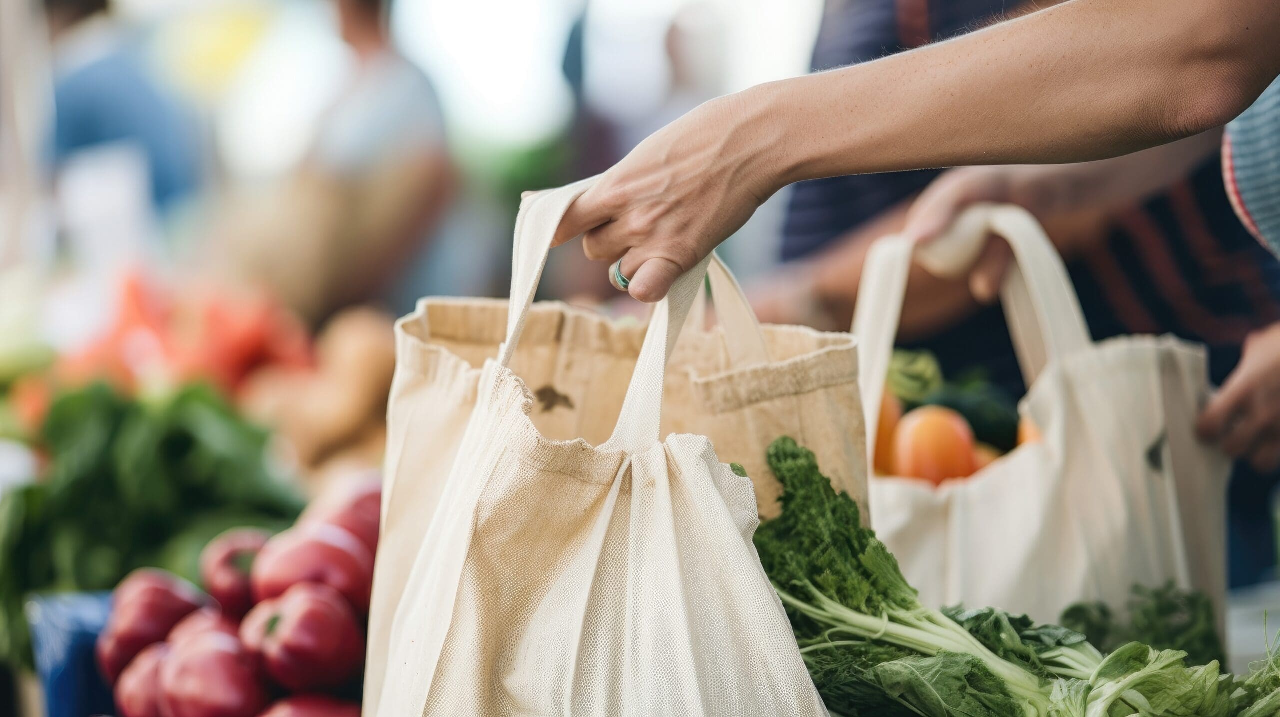 people shopping using a reusable tote bag at the farmers' market